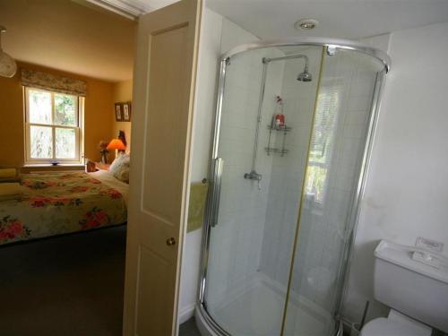 een badkamer met een douche, een toilet en een bed bij Garden Cottage in Alvescot