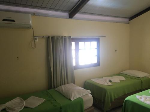 Habitación con 2 camas verdes y ventana. en Pousada Coco Verde Natal, en Natal