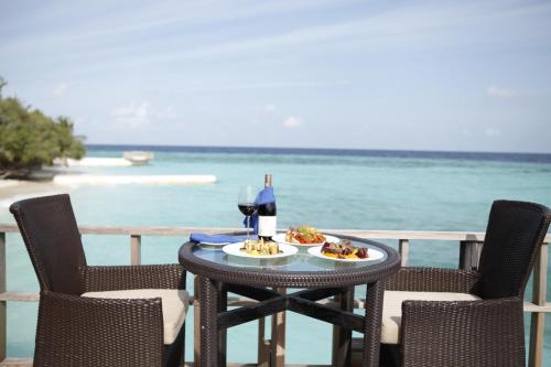 a table with a plate of food and a glass of wine at Eriyadu Island Resort in Reethi Rah
