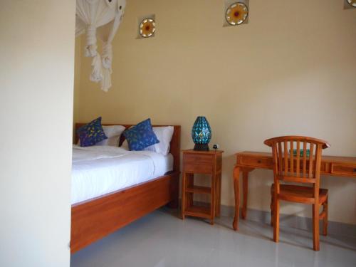 a bedroom with a bed and a table and a chair at Eko Homestay in Sidemen