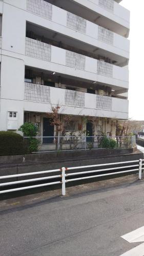 a white building with a fence next to a street at リバーサイド厚生町 in Okayama