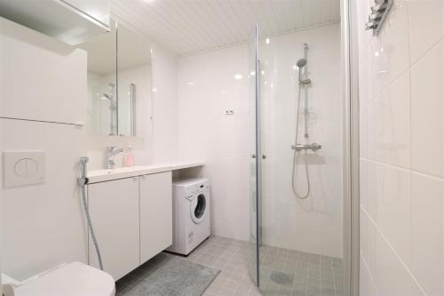 a white bathroom with a shower and a washing machine at Forenom Aparthotel Tampere Kaleva in Tampere