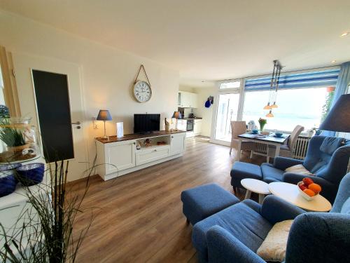 a living room with blue couches and a kitchen at Seeadler-F5 in Heiligenhafen