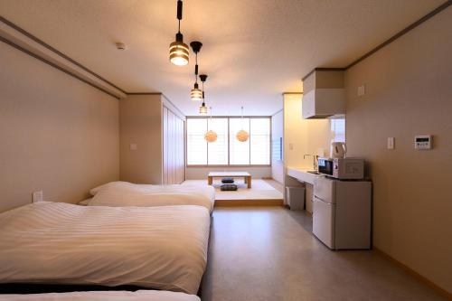 a room with two beds and a kitchen with a window at BEYOND HOTEL Takayama 3rd in Takayama