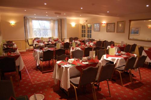 a room filled with tables and chairs with red carpet at The Carlton Hotel in Folkestone