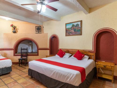 Hacienda Del Angel في باراس دي لا فونتي: غرفة فندق بسريرين ومخدات حمراء