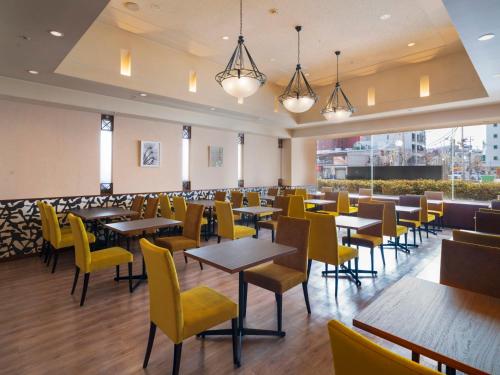 a dining room with tables and yellow chairs at ART HOTEL Aomori in Aomori