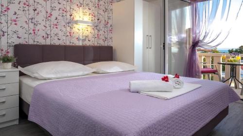 a bedroom with a purple bed with two towels at Apartments Angela in Baška Voda