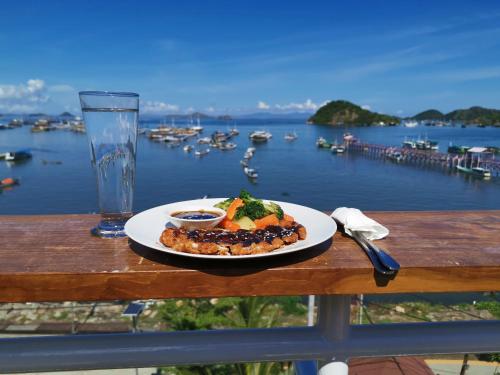 een bord eten op een tafel met uitzicht op een haven bij Flamingo Avia Labuan Bajo in Labuan Bajo