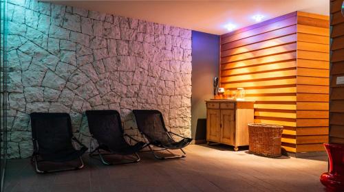 a room with three chairs and a stone wall at Residence Lastei in San Martino di Castrozza