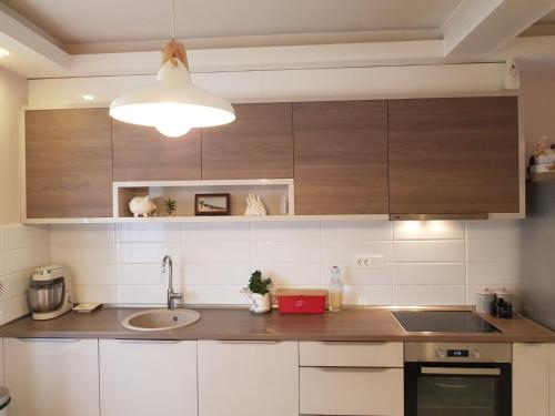 a kitchen with white cabinets and a sink and a light at Modern Apartment Doris in Kotor