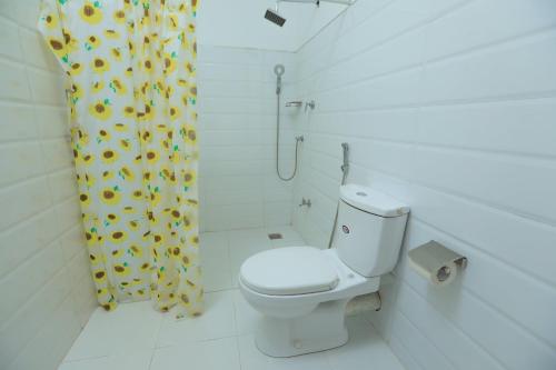 ein Badezimmer mit einem WC und einem Duschvorhang mit Sonnenblumen in der Unterkunft Trinco Star Cabana in Trincomalee