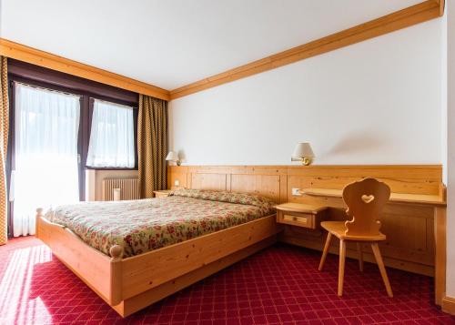 a bedroom with a bed and a desk and a chair at Residence Lastei in San Martino di Castrozza