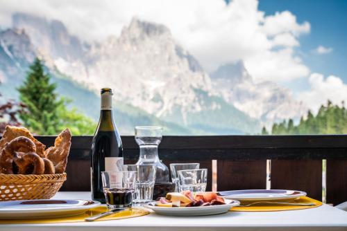 a table with a bottle of wine and a basket of bread at Residence Lastei in San Martino di Castrozza