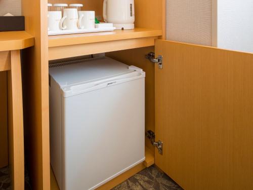 a small white washer and dryer under a shelf at Hotel Monterey Kobe in Kobe