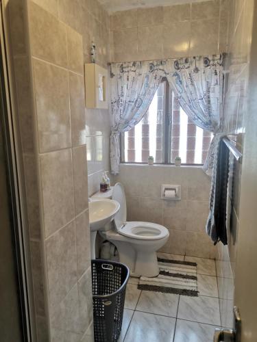a bathroom with a toilet and a sink and a window at Ithaca 9 Margate in Margate