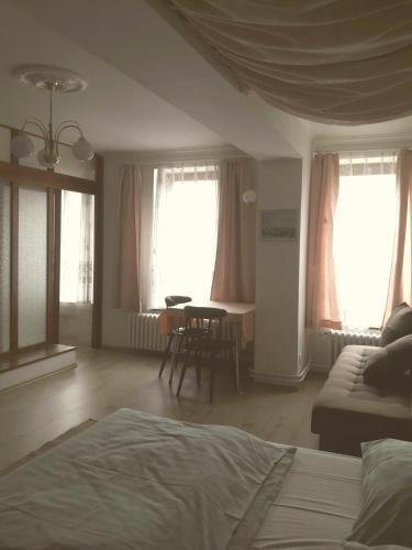 a bedroom with a bed and a table and windows at Apartmány Sedmikráska in Tehovec