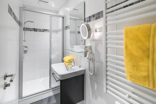 La salle de bains blanche est pourvue d'un lavabo et d'une douche. dans l'établissement Haus Inselzeit, à Norderney