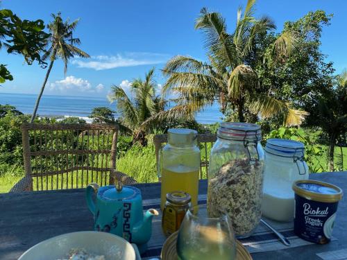 a table with jars of food and a view of the ocean at Balian Prana in Selemadeg