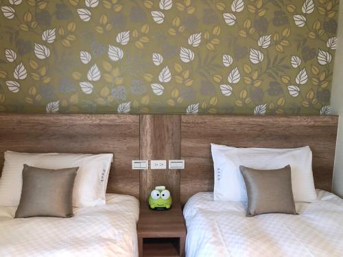 a bedroom with two beds and a wall with leaves at 太魯閣惠宇民宿 in Xincheng