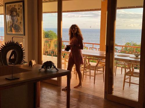 a woman standing in a living room looking out at the ocean at Balian Prana in Selemadeg