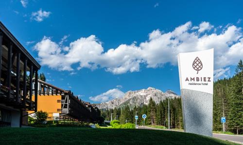 ein Schild vor einem Gebäude mit einem Berg in der Unterkunft Ambiez Residencehotel in Madonna di Campiglio