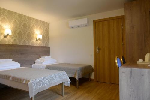 um quarto de hotel com duas camas e uma porta em Dzūkijos dvaro "Oficina" em Alytus