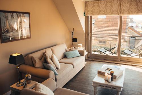 a living room with a couch and a large window at Residentie Duindoorn in Koksijde