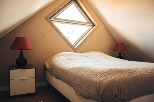 a attic bedroom with a bed and two lamps at Residentie Duindoorn in Koksijde