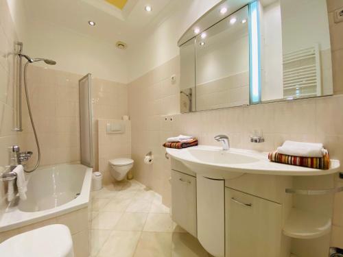 een badkamer met een wastafel, een bad en een toilet bij Villa Caprivi - Ferienwohnung 3 in Heringsdorf