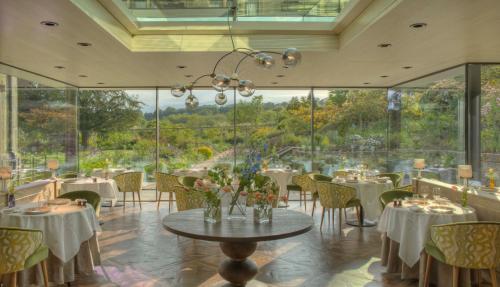 a restaurant with tables and chairs and large windows at Gravetye Manor in East Grinstead