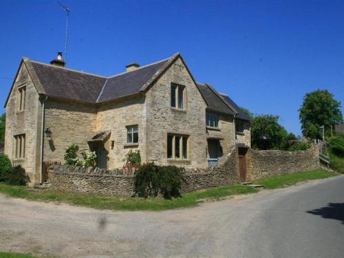 a large stone house with a stone wall at Hillside Cottage in Burford