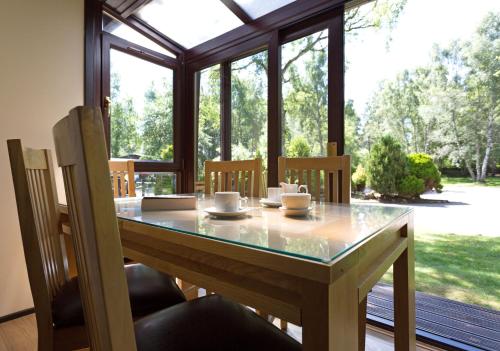 a dining room table with chairs and a glass counter top at Macdonald Lochanhully Resort in Aviemore