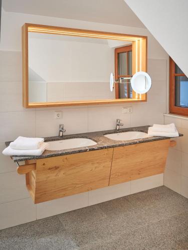 a bathroom with two sinks and a large mirror at Brunnwirt ESSEN & WOHNEN in Fuschl am See