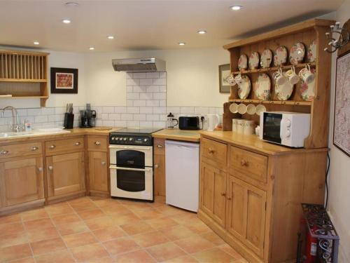 a kitchen with wooden cabinets and white appliances at The Folly at Castlebridge in Mere