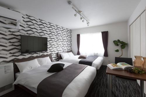 札幌市にあるホテルワンズレジデンスのベッド2台、薄型テレビが備わるホテルルームです。