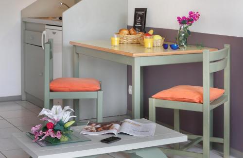 a kitchen with a small island with two stools and a table with flowers at Vacancéole - Résid'Price in Merville