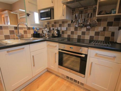 a kitchen with a sink and a stove top oven at Temple Mews in Stow on the Wold