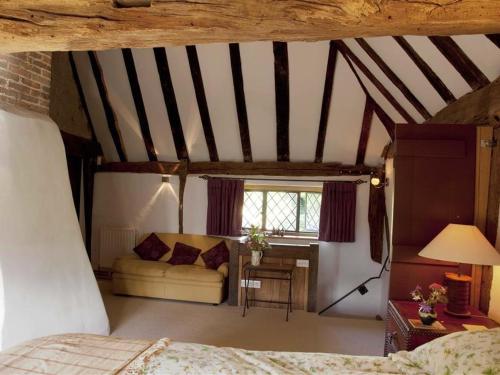The Yeoman's House في Bignor: غرفة نوم بسرير واريكة في غرفة