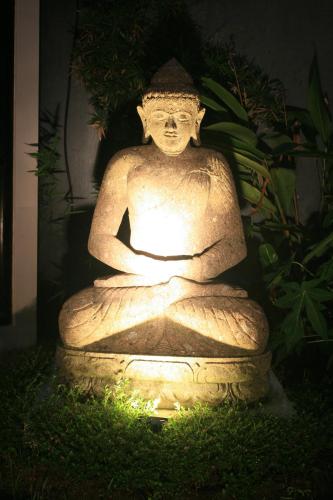 a stone statue sitting in the grass at night at Katala Suites and Villas in Sanur