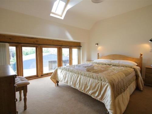 a bedroom with a bed and a large window at Tithe Barn, Lyneham in Bruern
