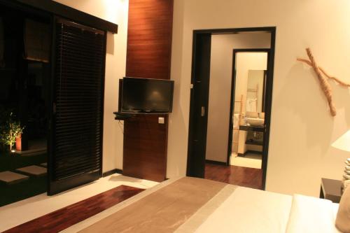 a living room with a television and a bedroom at Katala Suites and Villas in Sanur