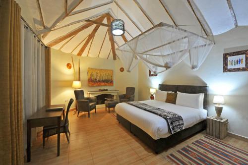 Habitación de hotel con cama, escritorio y mesa. en Gorilla Safari Lodge, en Rubuguli