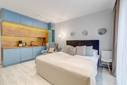 a bedroom with a large bed and a kitchen at Apartamenty Rondo in Świnoujście
