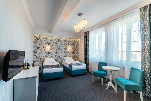 een hotelkamer met 2 bedden en een tafel en stoelen bij Margerita in Modlnica