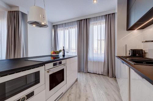 a kitchen with white cabinets and a black counter top at Apartamenty Rondo in Świnoujście