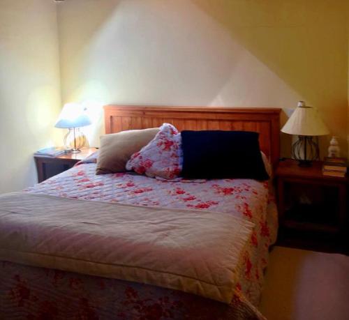 a bed in a bedroom with two lamps and two tables at Casa adosada con piscina en Agoustrina in Angoustrine