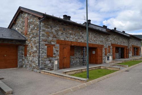 a stone building with wooden doors on a street at Casa adosada con piscina en Agoustrina in Angoustrine