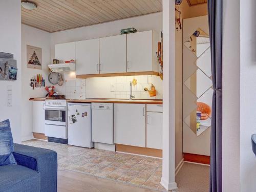 a kitchen with white cabinets and a blue couch at 4 person holiday home in Gudhjem in Gudhjem
