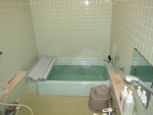 y baño alicatado con bañera. en Pension Marionette en Hakuba